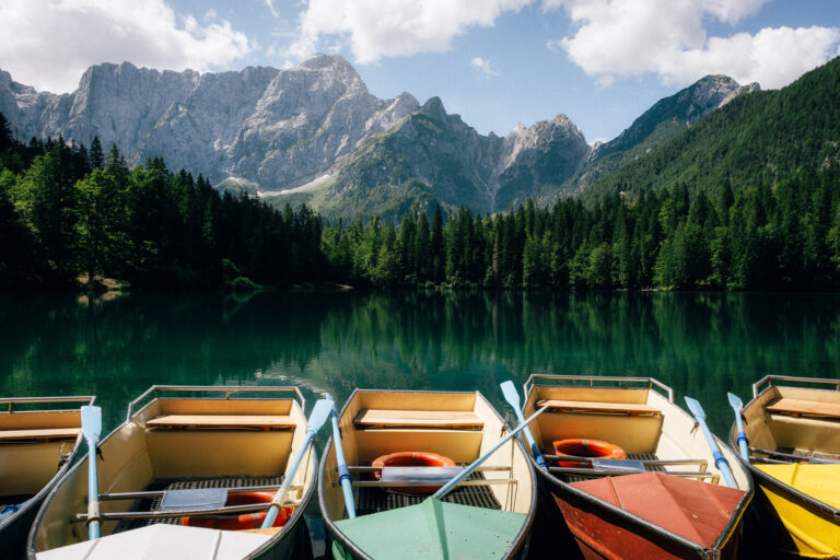 Rowboats lined up at a still alpine lake beneath the peaks