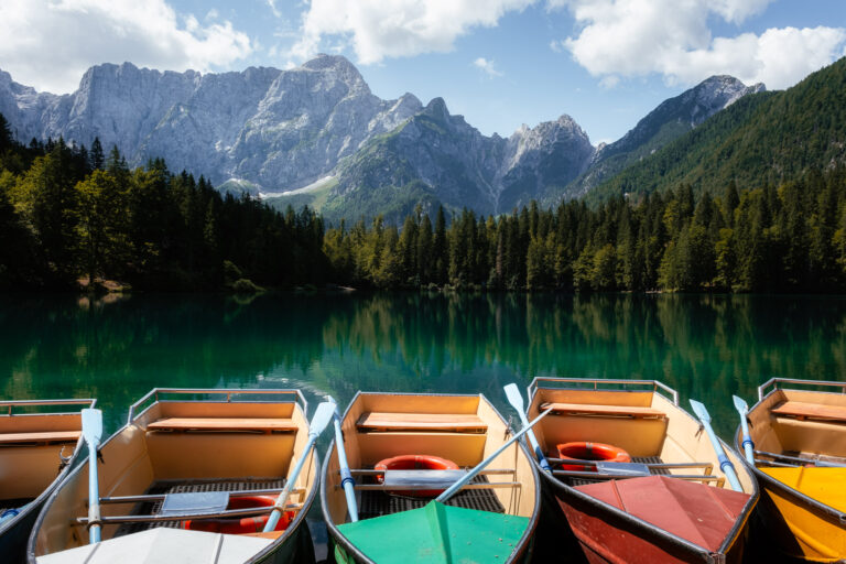 Rowboats lined up at a still alpine lake beneath the peaks