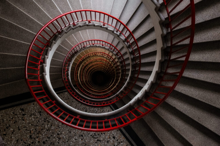 A spiral staircase winds down into the dark