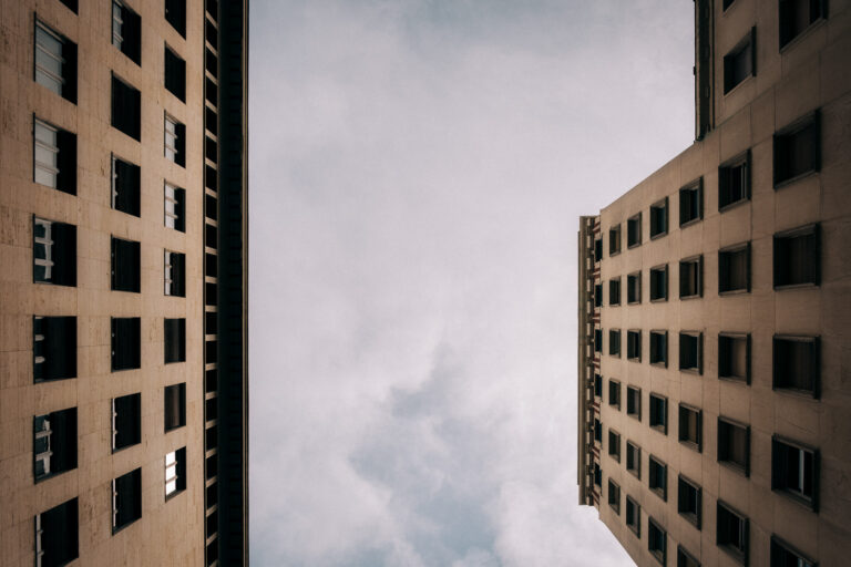 Two buildings reach toward a canyon of clouds